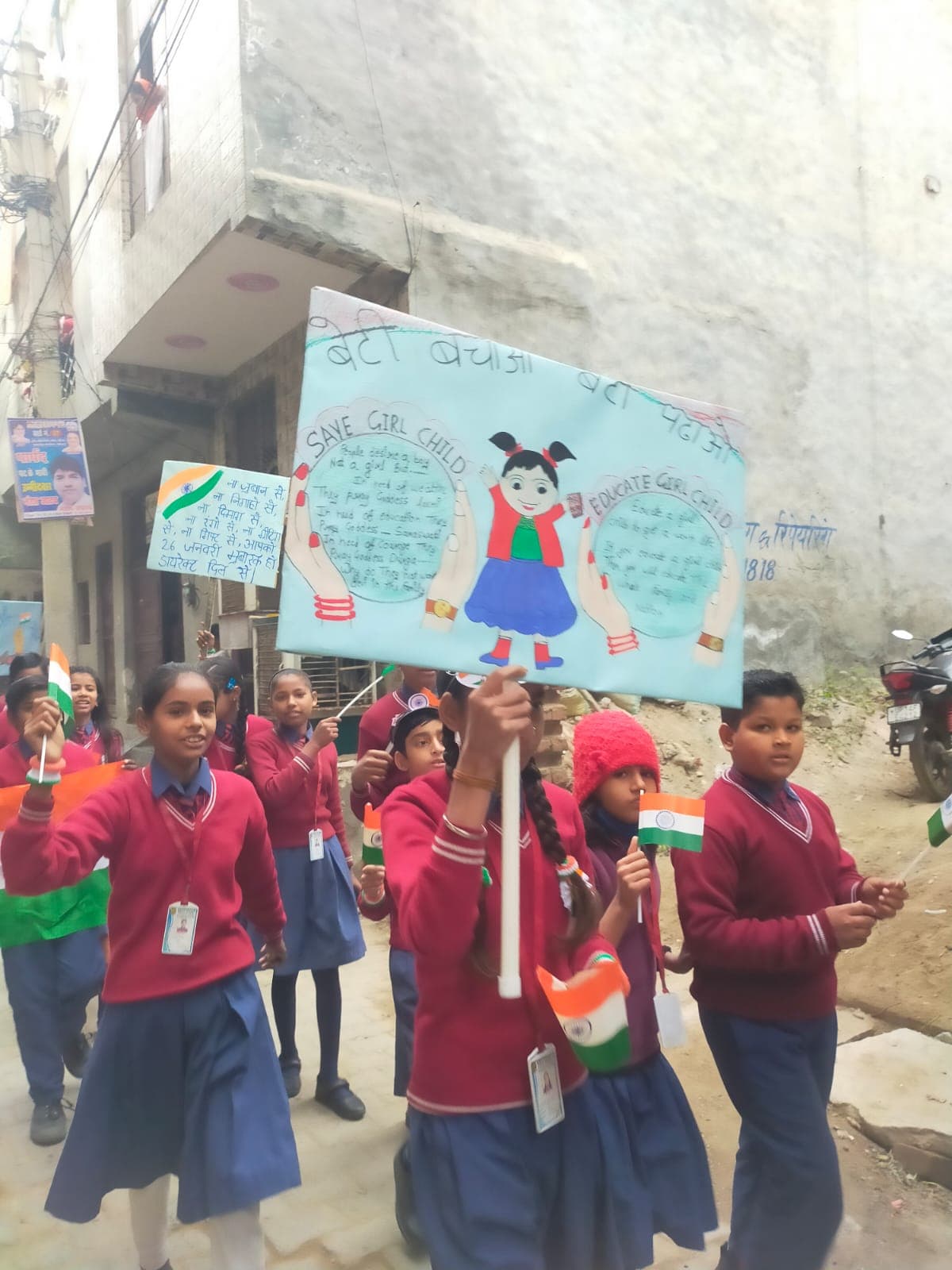 Students marching with a Save the Girl Child poster and the national flag